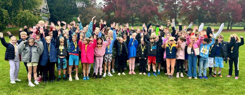 Group of children in a park cheering and wearing medals