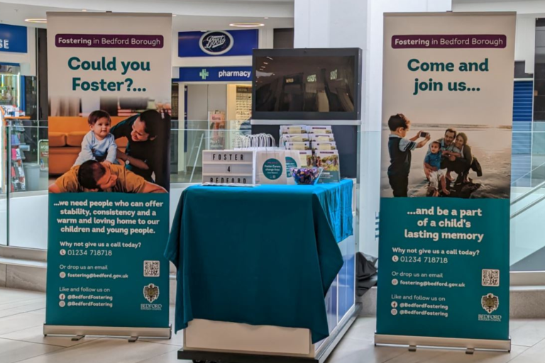 Pop up banners and table in shopping centre promoting Fostering information events
