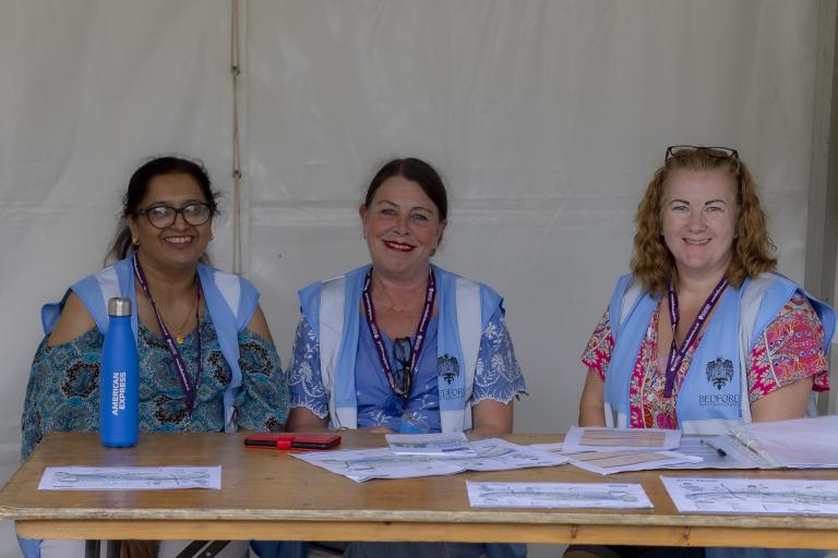 Three females sat behind desk smiling