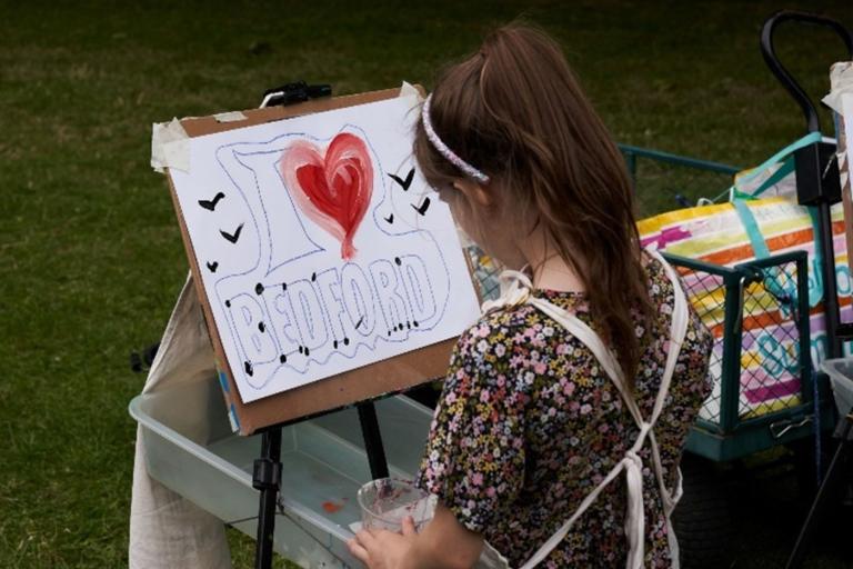 Child with painting that says I love Bedford