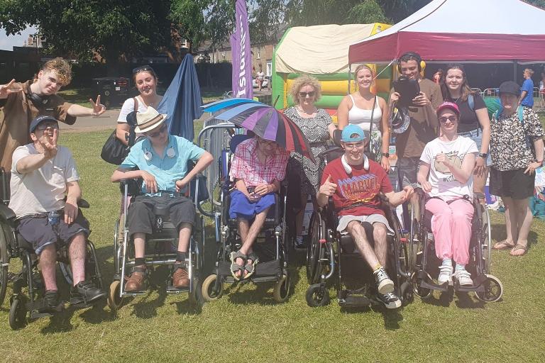 Line of people sat in wheelchairs in a park
