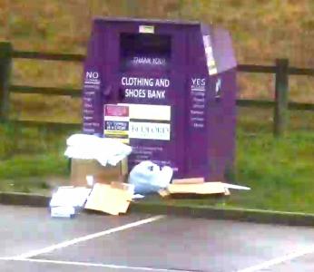A pile of rubbish dumped in front of a clothing and shoes recycling bank