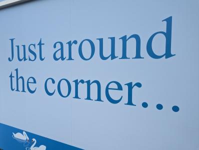 Vinyl on the former Beales and Debenhams buildings that says "Just around the corner...".
