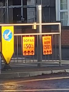 Posters advertising a sofa sale tied to railings in a street