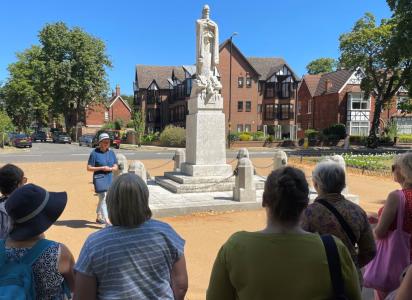 A group of visitors listening to a tour guide in front of a statue