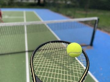 Tennis racket and ball with a tennis court in the background