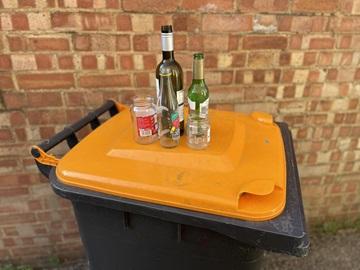 Glass bottles and jars on an orange-lidded bin