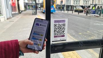 Journey Alerts QR code being scanned at a bus stop by a mobile phone