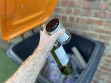 Glass bottle and jar going into orange-lidded bin