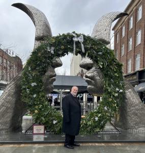 Mayor of Bedford Borough, Tom Wootton, in front of the Christmas wreath on the Silver Faces statue
