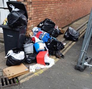 Fly-tipping in Bedford - an overflowing black bin surrounding by rubbish and black bags