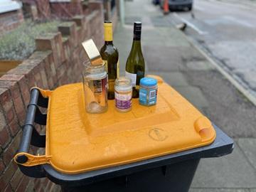 Glass bottles and jars on an orange-lidded bin
