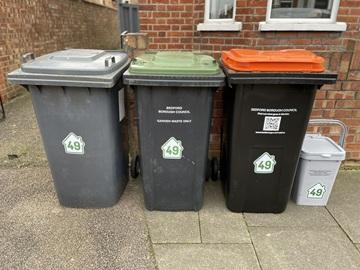 Residential bins on street - black bin, green-lidded, orange-lidded, grey food caddy