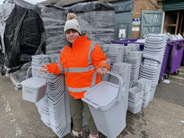 Councillor Nicola Gribble with a kitchen caddy and outdoor bin for food waste 