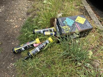 Nitrous oxide canisters laying on grass, some in a cardboard box
