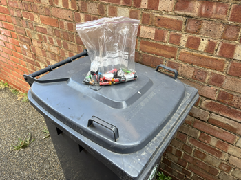 Sealed clear bag of batteries on a wheelie bin