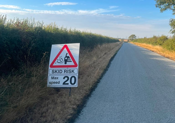 A newly resurfaced road with a warning sign for drivers
