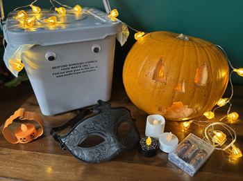 A food waste caddy, carved pumpkin, and Halloween decorations