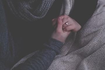 two people holding hands under a blanket