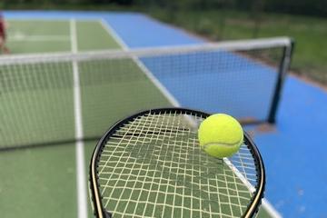 Tennis racket and ball with a tennis court in the background