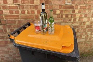 Glass bottles and jars on an orange-lidded bin