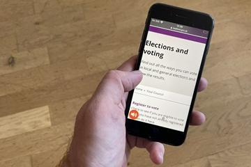 A mobile phone in a hand with an elections website displayed