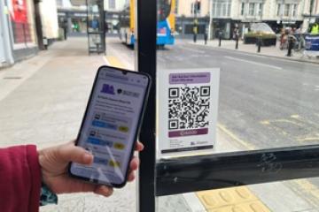 Journey Alerts QR code being scanned at a bus stop by a mobile phone