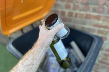 Glass bottle and jar going into orange-lidded bin