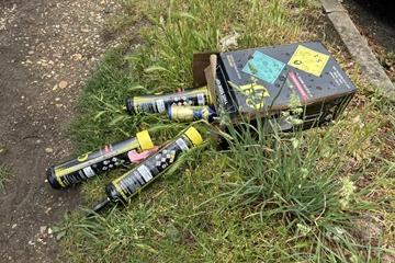 Nitrous oxide canisters laying on grass, some in a cardboard box