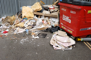 Fly-tipped waste piled by a bin