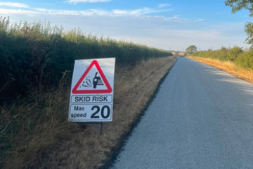 A newly resurfaced road with a warning sign for drivers