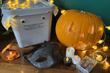 A food waste caddy, carved pumpkin, and Halloween decorations