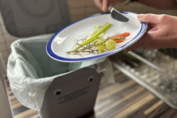 Plate being scraped into food waste kitchen caddy