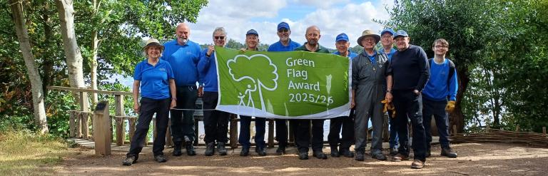 Group of park volunteers holding banner with text Green Flag Awards 2025/6