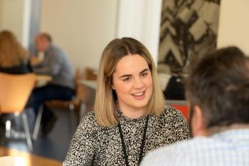 Young woman talking at a table in a relaxed staff canteen setting